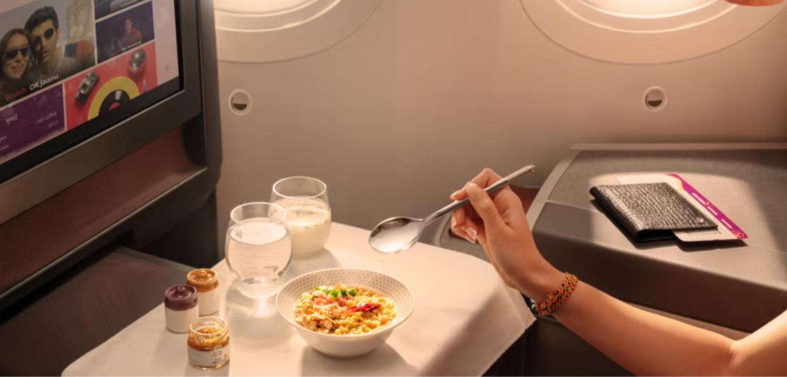 Air India Business Class table with the new Martaban-inspired cruet set beside a bowl, glassware and a seatback screen