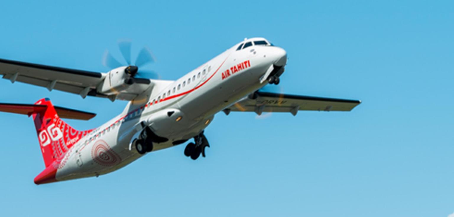 An Air Tahiti ATR 72 climbing away from Papeete against a blue sky, gear retracting