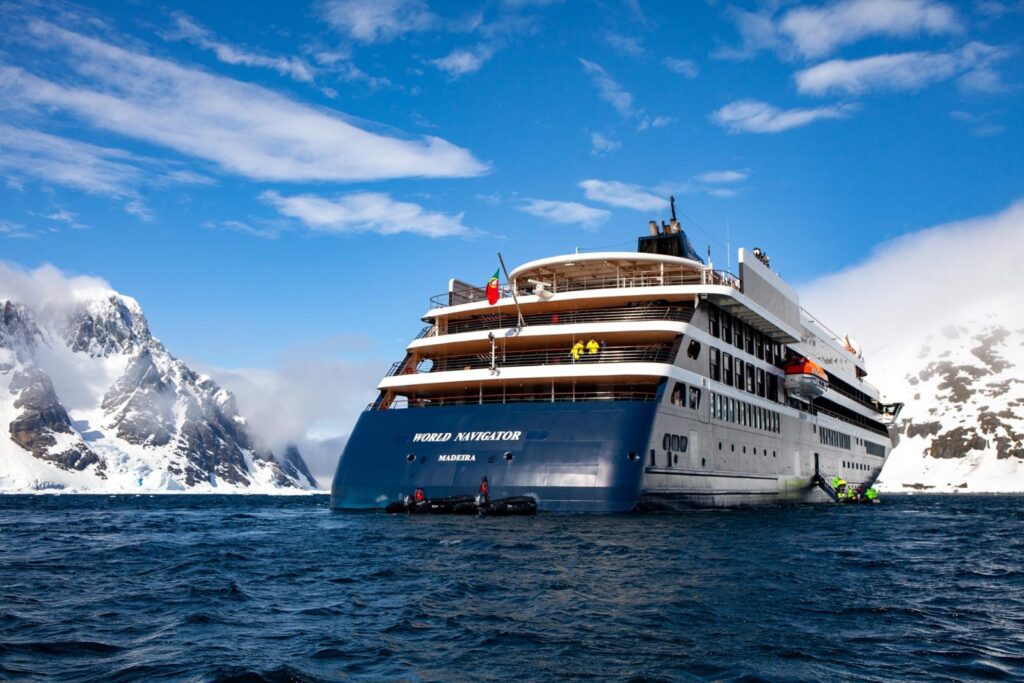 Atlas Ocean Voyages Antarctica expedition: aerial view of World Navigator sailing between snow-covered peaks