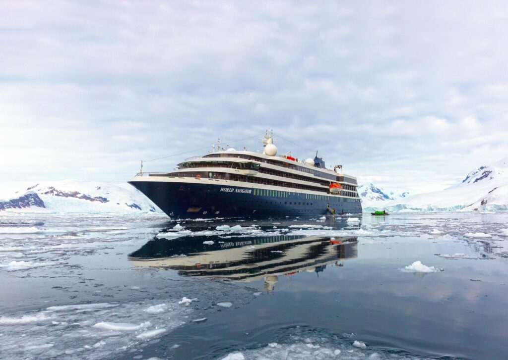 Atlas Ocean Voyages World Navigator on calm water among floating ice and glaciers in Antarctica