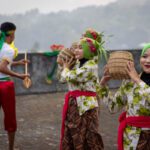 Dancers in green headscarves carrying woven baskets during a traditional dance at Fort Belgica, Banda Neira