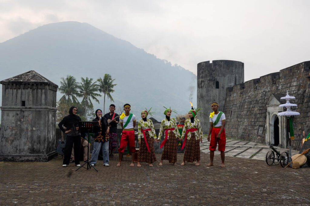 Bandanese dancers and musicians performing on Fort Belgica with the Gunung Api volcano behind, Banda Neira