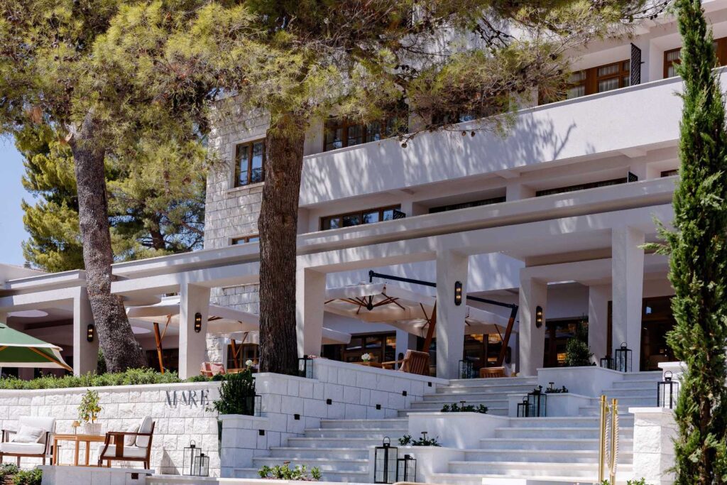The Bristol Bol hotel facade and stone steps under pine trees in Bol, Brac
