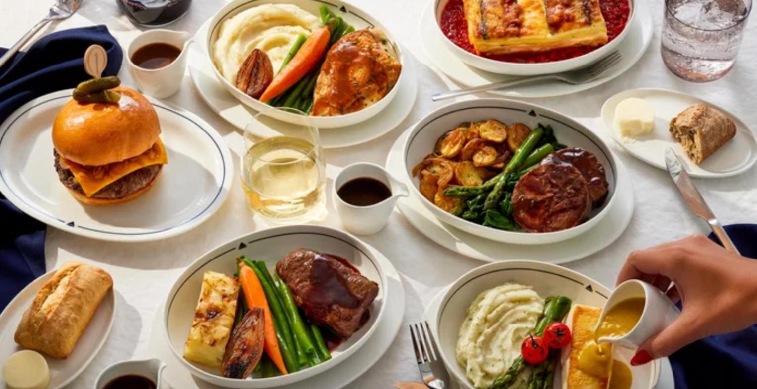 The new Delta One entree line-up on white tableware: Wagyu burger, braised lamb, beef short rib, sea bass and roast chicken with sides