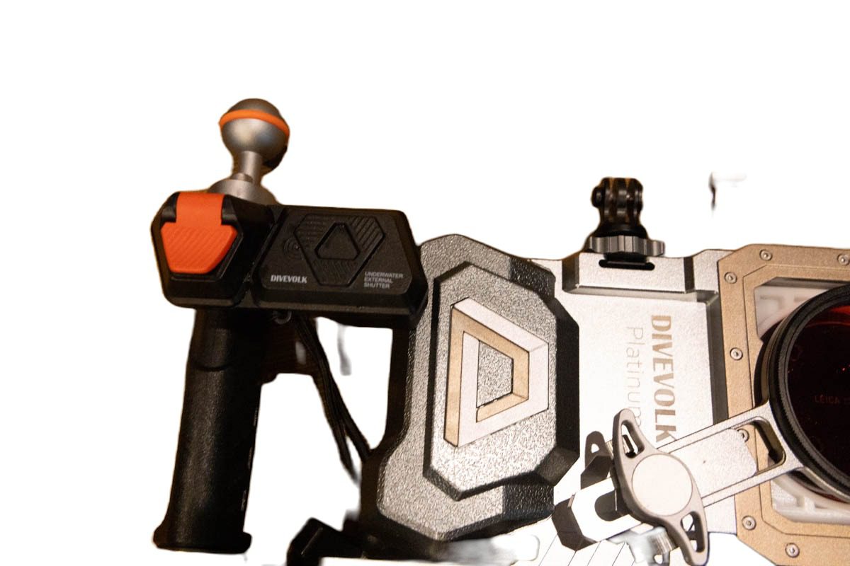 DIVEVOLK external Bluetooth shutter with its orange trigger, clamped to the left handle of the dual-handle tray