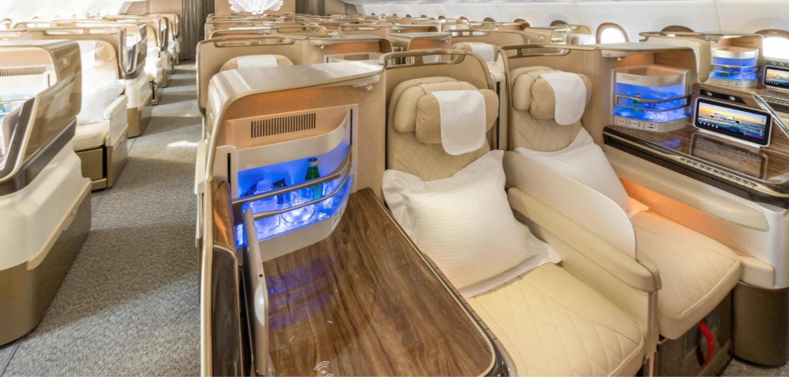 Emirates A350 business class cabin in cream leather and wood, 1-2-1 layout with a lit minibar and pillows on the centre seats