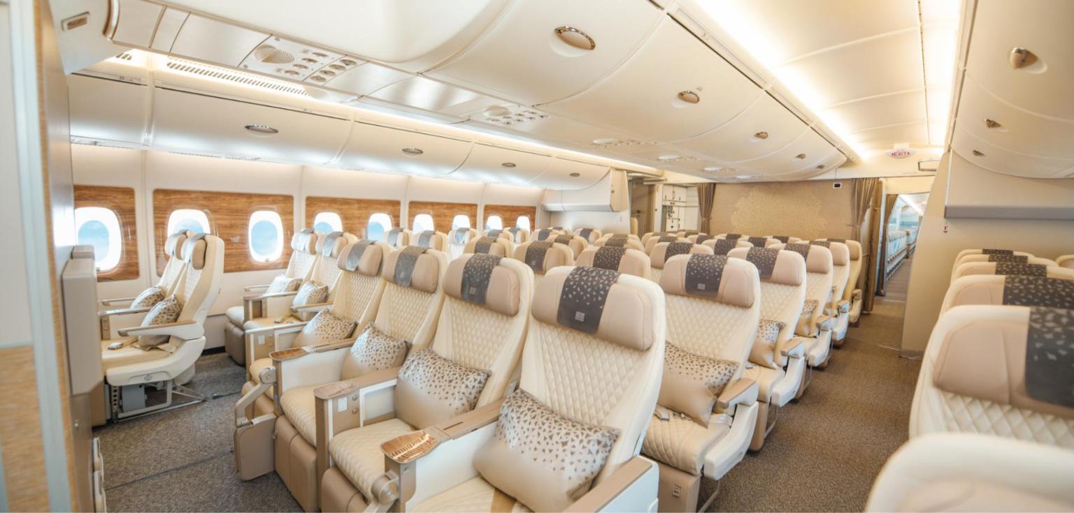 Emirates A350 premium economy cabin with cream leather seats, patterned pillows and wood-finish window surrounds