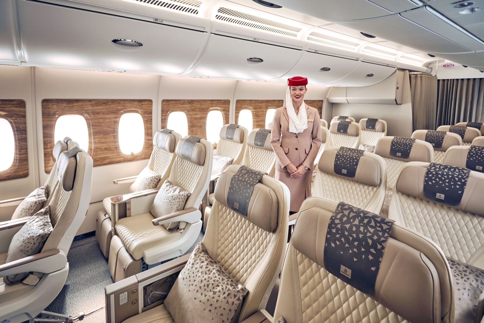 Premium Economy cabin on a retrofitted Emirates A380, cream leather seats in a 2-4-2 layout with cabin crew