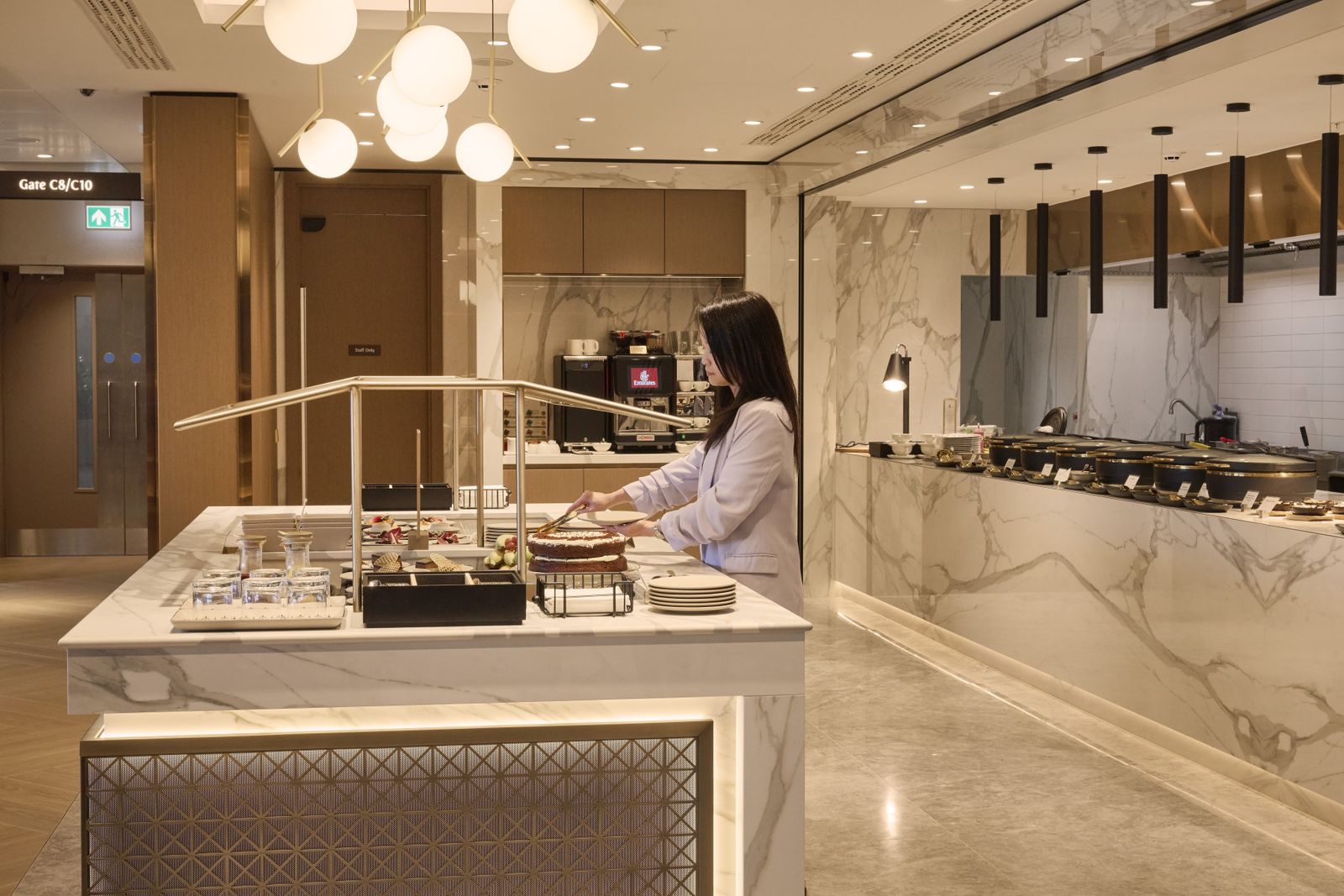 Open-kitchen food counter with a staff member in the Emirates lounge at Manchester Airport