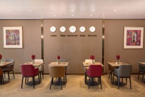 Dining area of the Emirates new lounge at Manchester Airport Terminal 2, with tables and world clocks on the wall