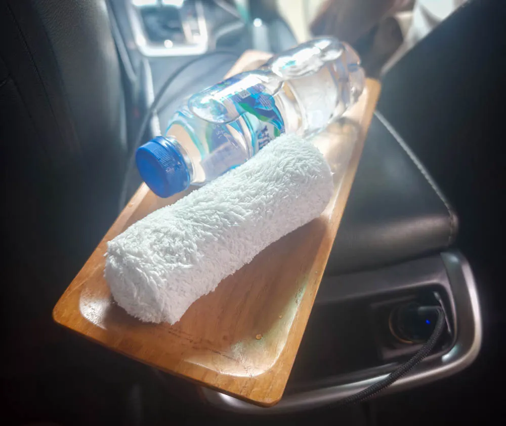 Cold towel and bottle of water on a wooden tray in the Goddess Retreats transfer car