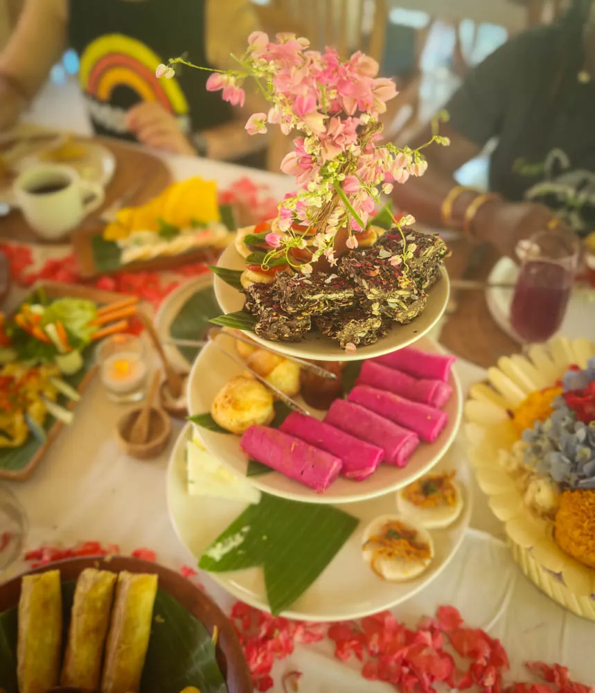 Farewell high tea with cakes, pink dragon-fruit crepes and flowers on a tiered stand