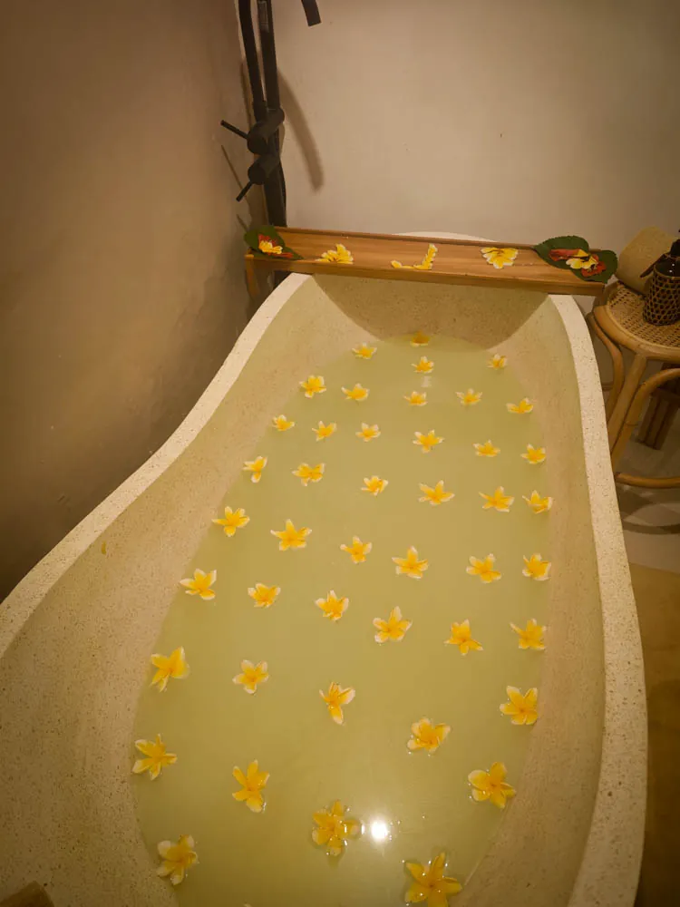 Egg-shaped bathtub filled with milky water and floating frangipani flowers in the spa