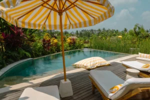 Infinity pool of the Frangipani Villa at Goddess Retreat Ubud, with yellow-striped umbrella, loungers and rice fields beyond