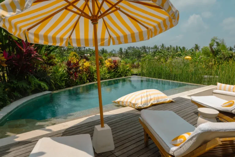 Goddess Retreat Ubud Review: A Wellness and Creative Retreat in Bali That Reset My Nervous System Infinity pool of the Frangipani Villa at Goddess Retreat Ubud, with yellow-striped umbrella, loungers and rice fields beyond