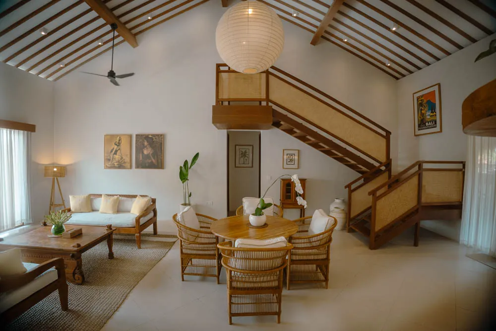 Double-height living room of the Frangipani Villa with teak sofas, cane chairs and a paper-lantern pendant