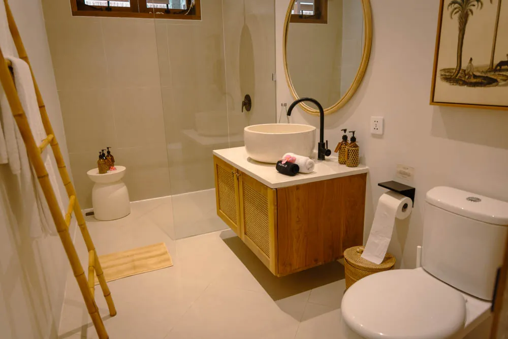 Ensuite bathroom with rain shower, round mirror and wooden vanity in the Gaia room, Goddess Retreat Ubud