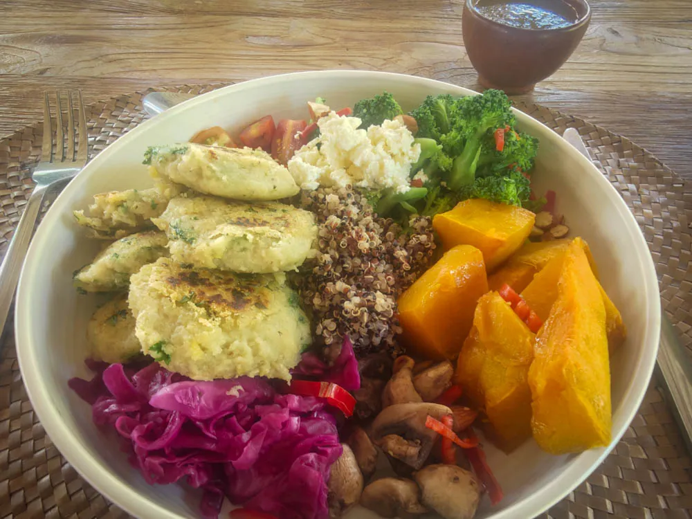Healthy lunch bowl with quinoa, fritters, pumpkin, red cabbage and greens at Goddess Retreat Ubud