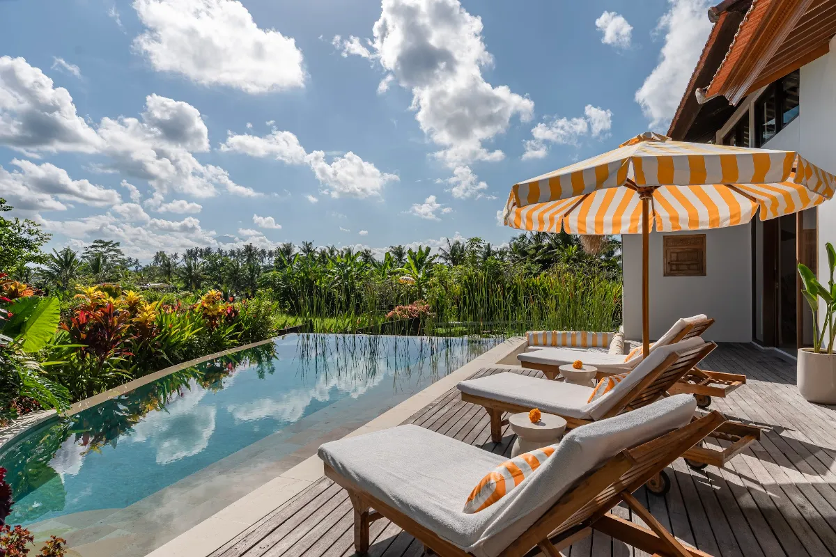Infinity pool with loungers and striped umbrella overlooking the rice fields at Goddess Retreat Ubud
