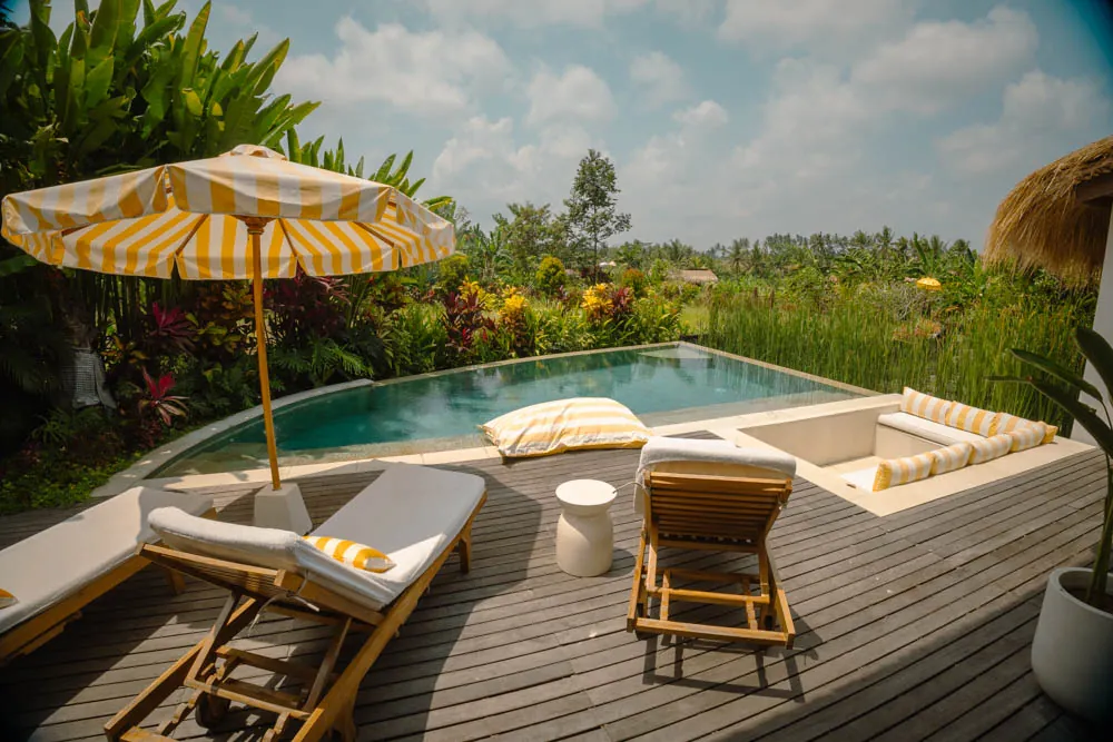 Teak pool deck with striped umbrella and loungers at a private pool villa, Goddess Retreat Ubud