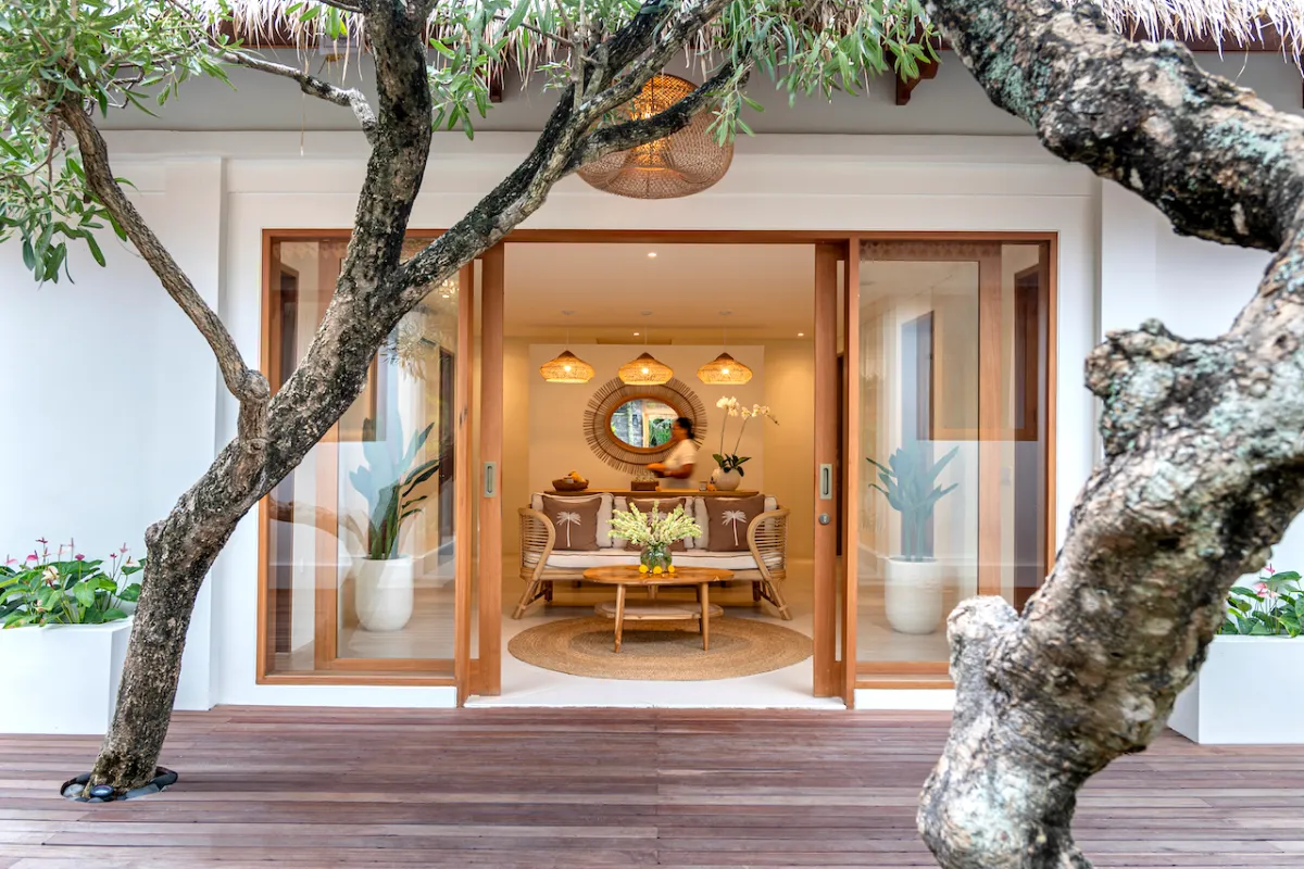 Glass doors opening into the spa lounge at Goddess Retreat Ubud, framed by frangipani trees
