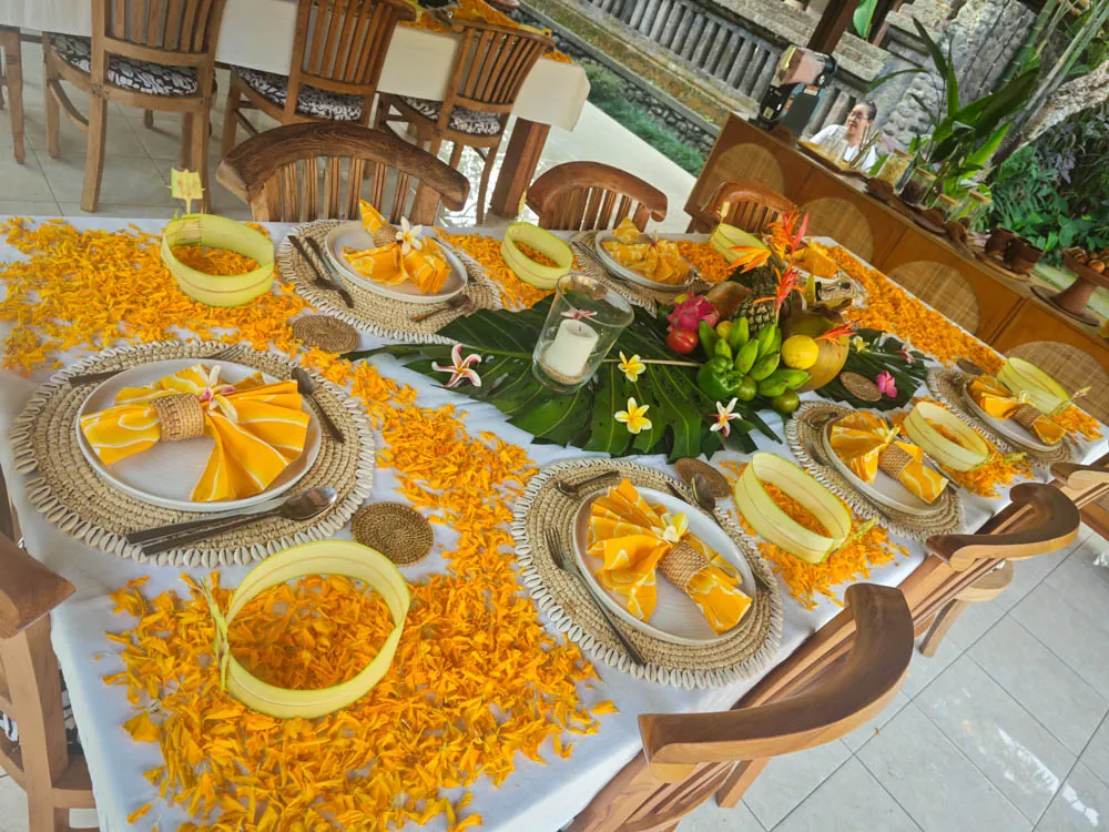 Dinner table decorated with marigold petals, yellow napkins and woven placemats at Goddess Retreat Ubud