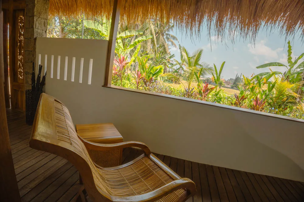 Wooden lounger on a covered villa terrace overlooking a tropical garden at Goddess Retreat Ubud