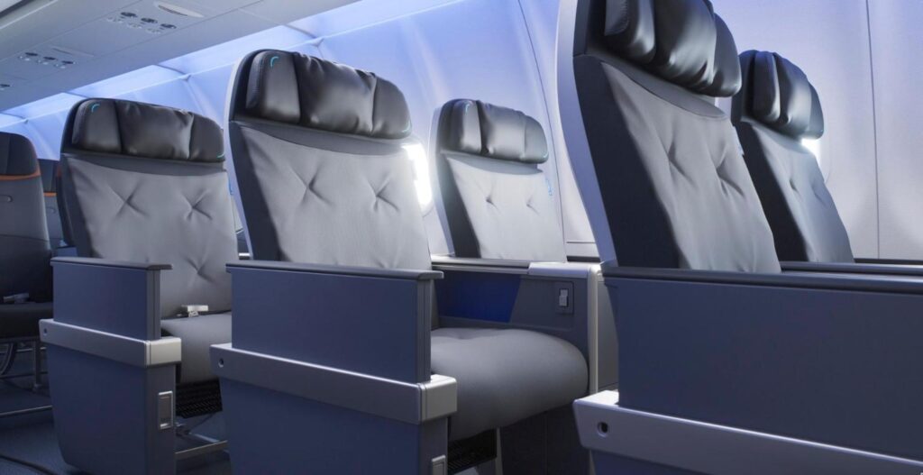 JetBlue BlueFirst domestic first class seats in a 2-2 layout with grey upholstery, winged headrests and blue-lit cabin