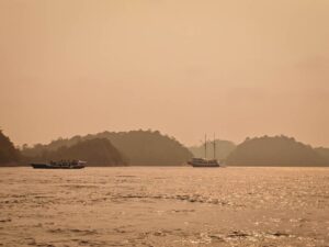 Liveaboards at anchor in Misool under an orange forest-fire haze