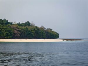 White-sand beach of Molana Island under a grey sky