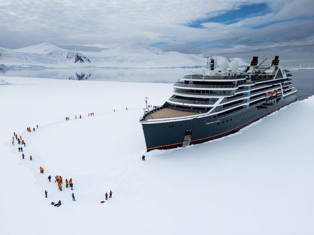 Seabourn Antarctica voyage: an expedition ship moored in sea ice while a line of guests walks across the snow
