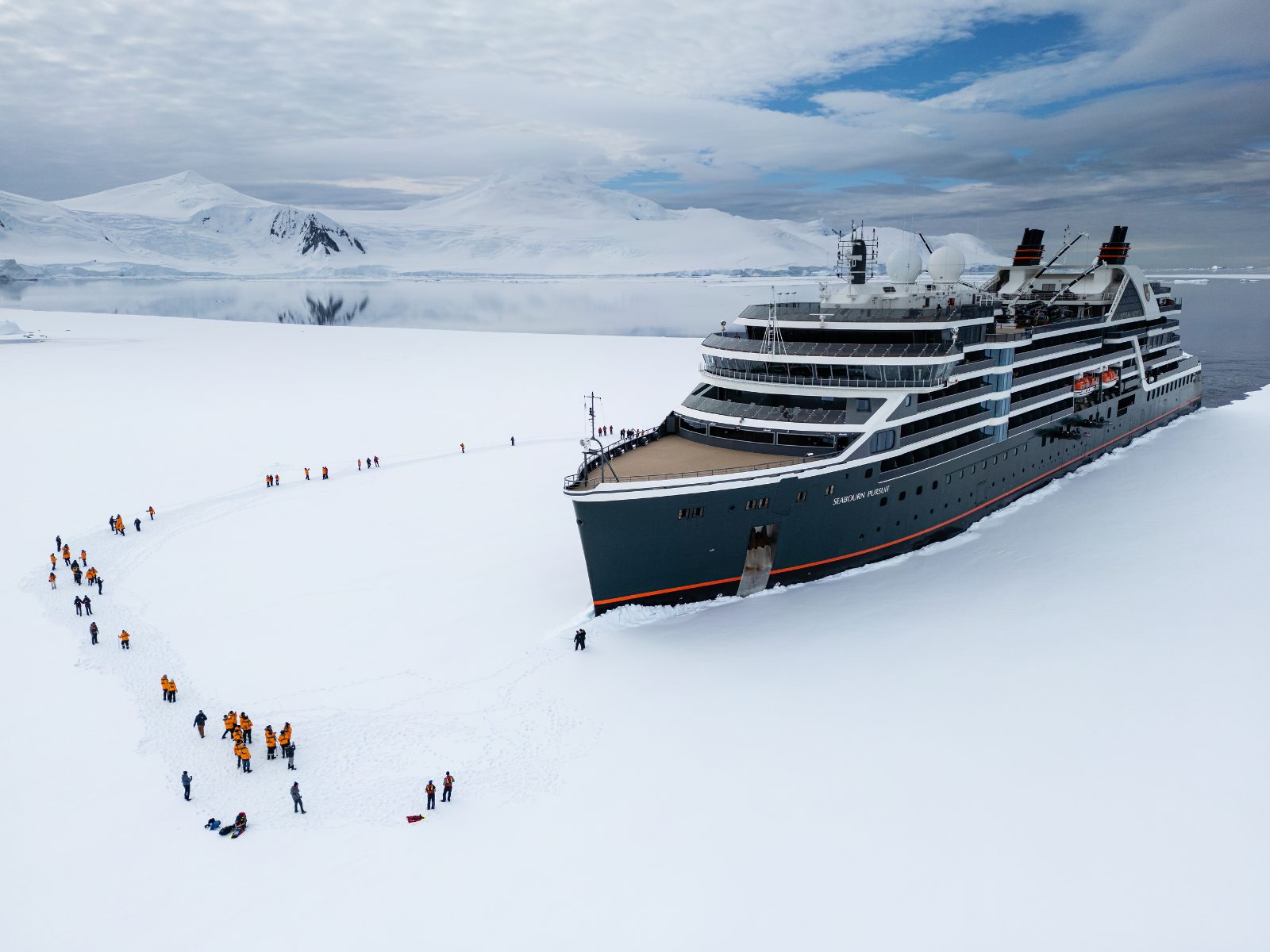 Seabourn Antarctica voyage: an expedition ship moored in sea ice while a line of guests walks across the snow