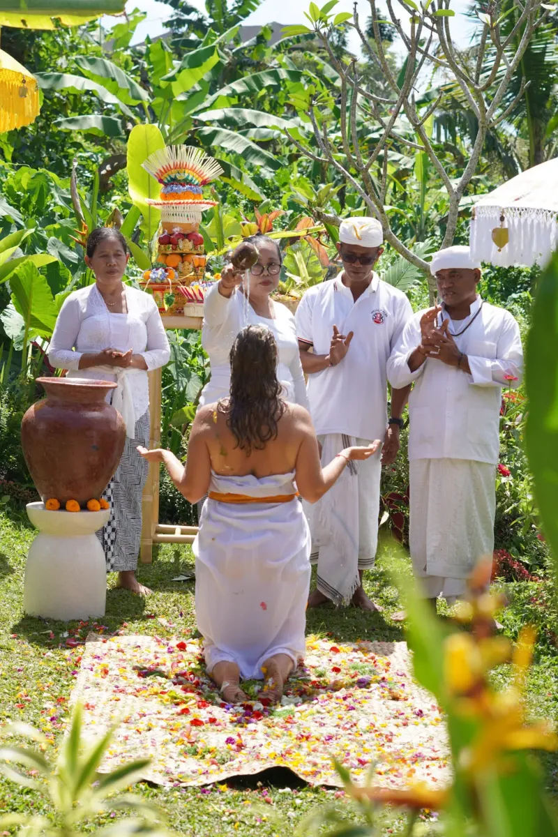 Guest receiving a Tri Desna blessing from Balinese priests in white ceremonial dress, Ubud