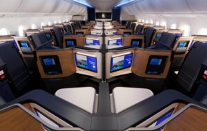 Rendering of the United Elevated 787-9 Polaris cabin with doored suites, wood-grain panels and large seatback screens showing a welcome message