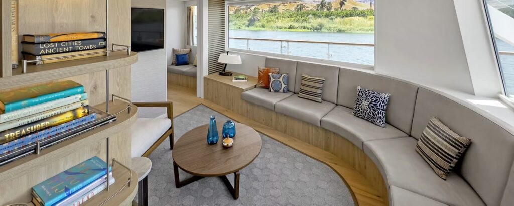 Explorer Suite on Viking Aton, the Nile sister ship of Viking Sekhmet, with a curved sofa, bookshelves and windows onto a private veranda